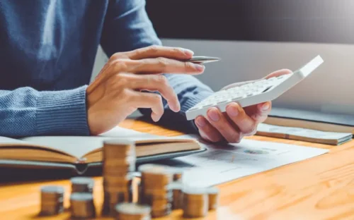 hombre calculando sus cuentas por pagar en una calculadora 