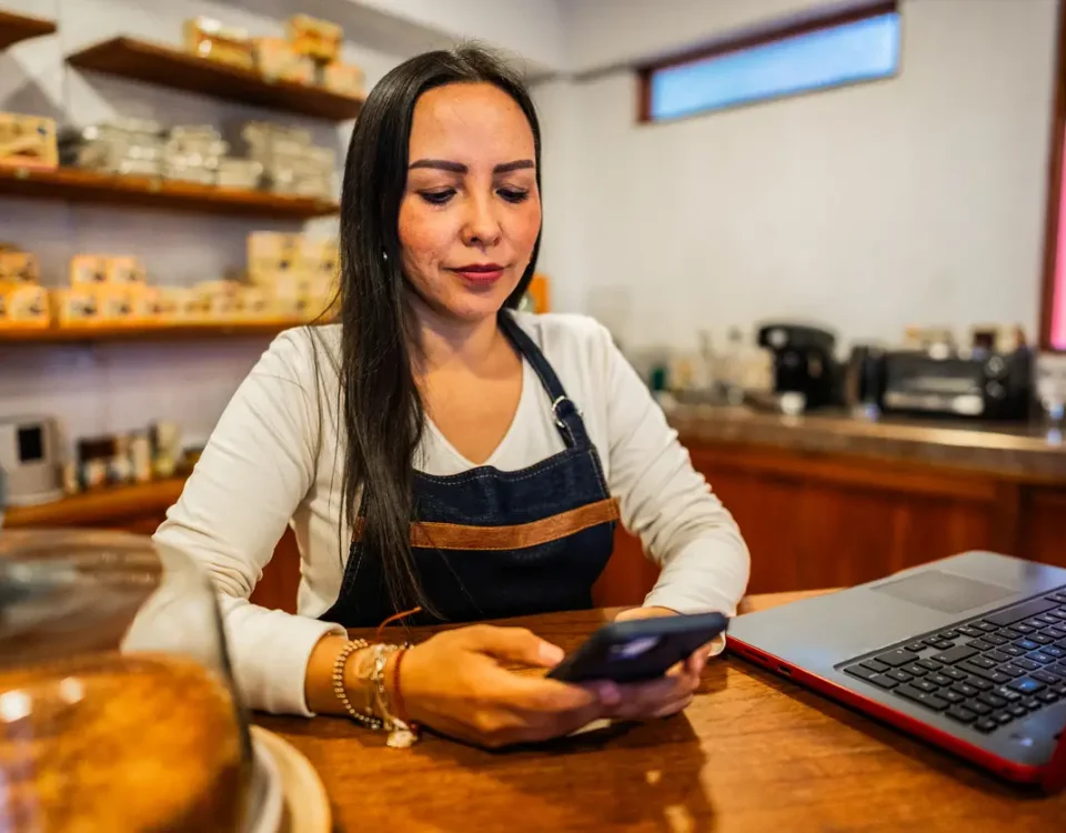 Dueña de negocio revisando el control de stock desde su celular en el mostrador de la tienda.
