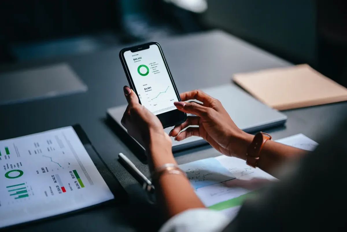 Aplicación de control de stock mostrando reportes de ventas y gráficos financieros en la pantalla de un celular.
